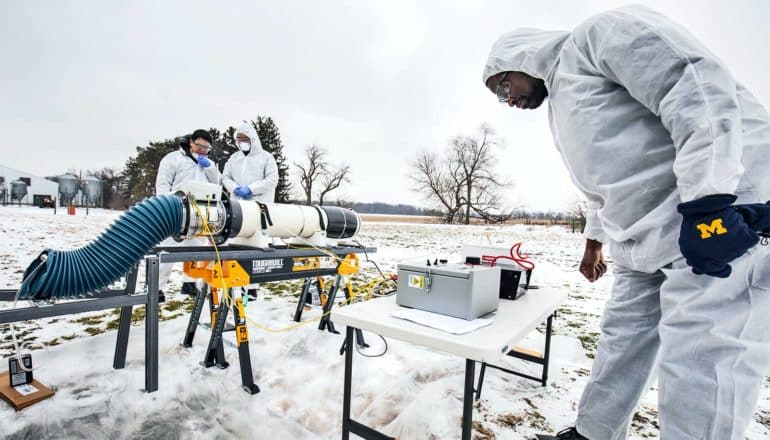 Researchers use a nonthermal plasma reactor outdoors to inactivate Porcine Reproductive and Respiratory Syndrome virus on a snowing field as they wear white protective gear.