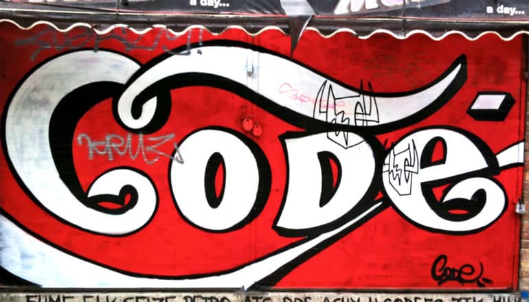 Graffiti on a wall reads "Code" in the Coca-Cola font