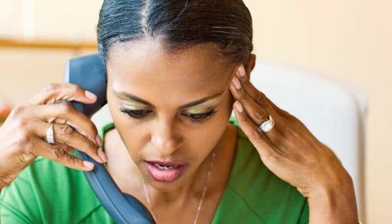 black person looks frustrated while speaking into phone