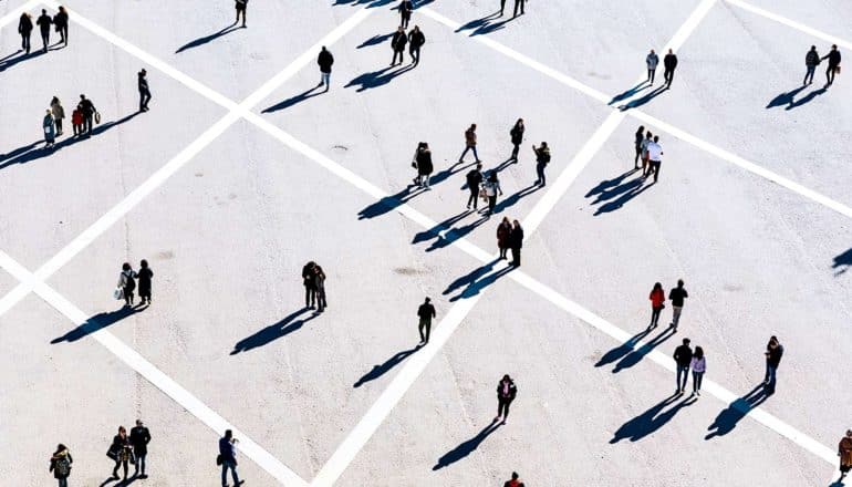 People walk on a plaza covered in white lines