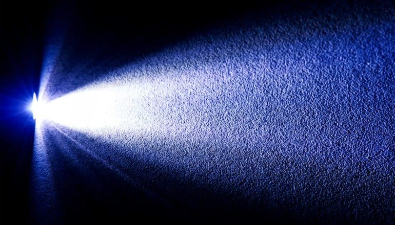 A blue flashlight shines on a wall