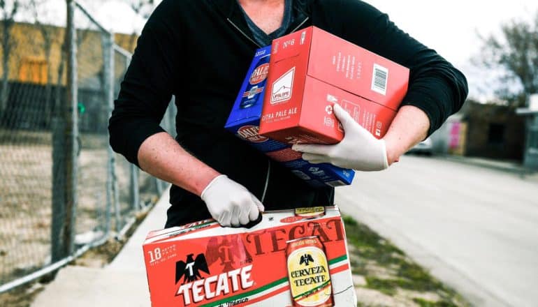 person wearing gloves holds boxes of beer