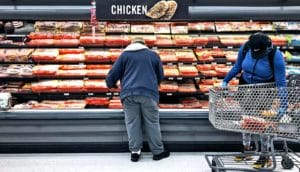 Shoppers in a grocery store browse the meat selection