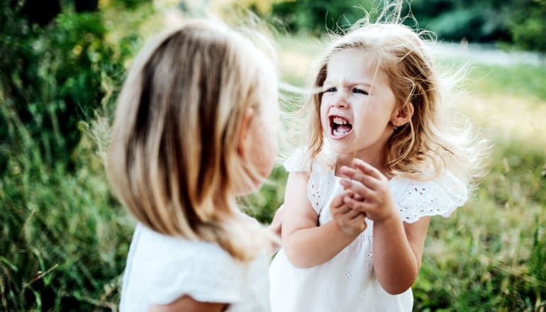 One young girl in white yells at another