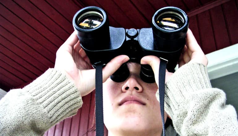 A young woman looks through binoculars