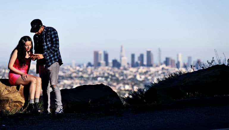 Two people look at a photo they just took of the clear skies over Los Angeles, which is in the background