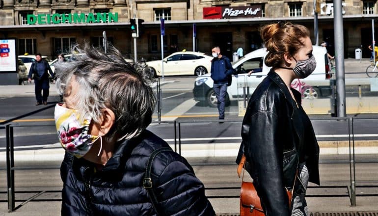 Two women pass each other on the street, both wearing face masks