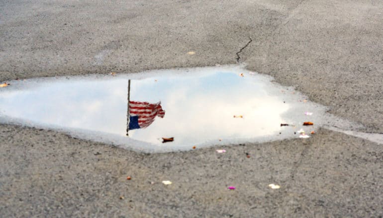 reflection of US flag in puddle