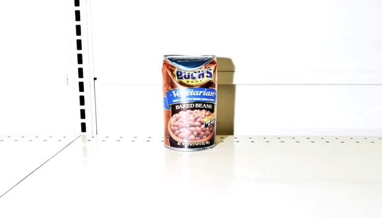 A single dented can of baked beans is the last on the grocery store shelf