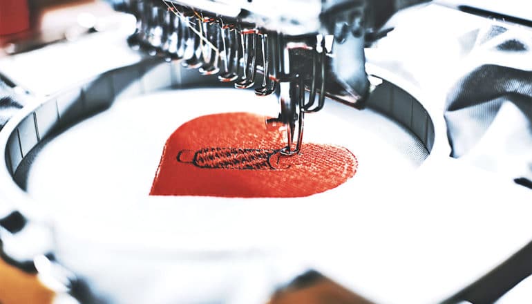 An embroidery machine stitches a heart