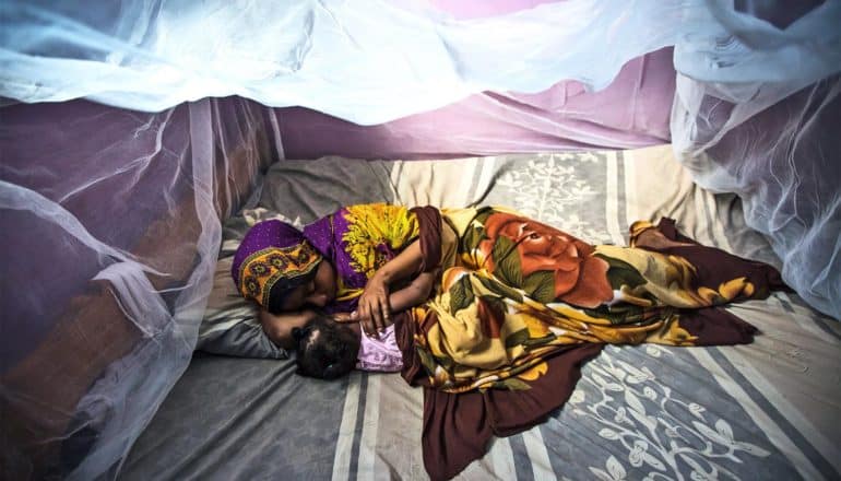 A mother and child sleep under malaria nets