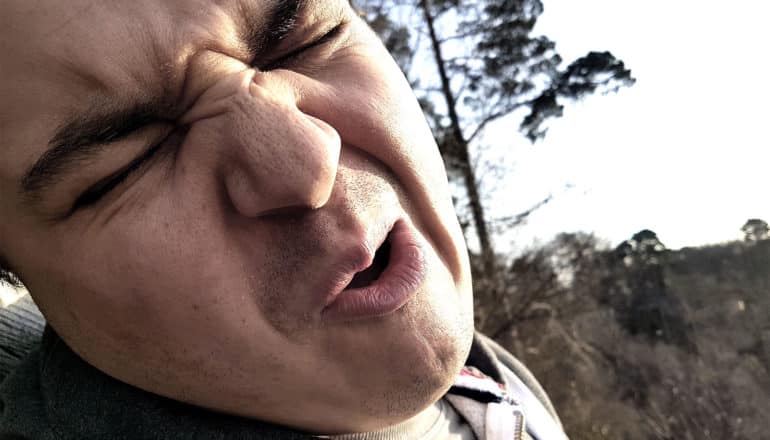 A man grimaces in pain while outside