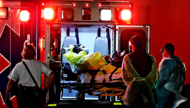 Emergency medical workers place a patient on a gurney in an ambulance