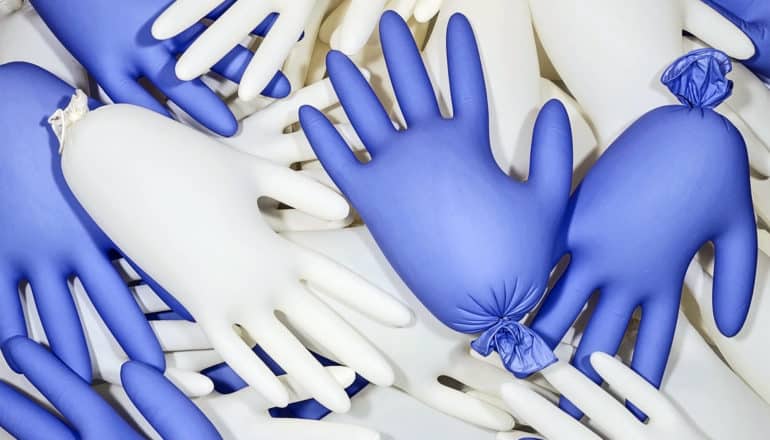 A bunch of surgical gloves, some white and some purple, are filled with air and tied off like balloons