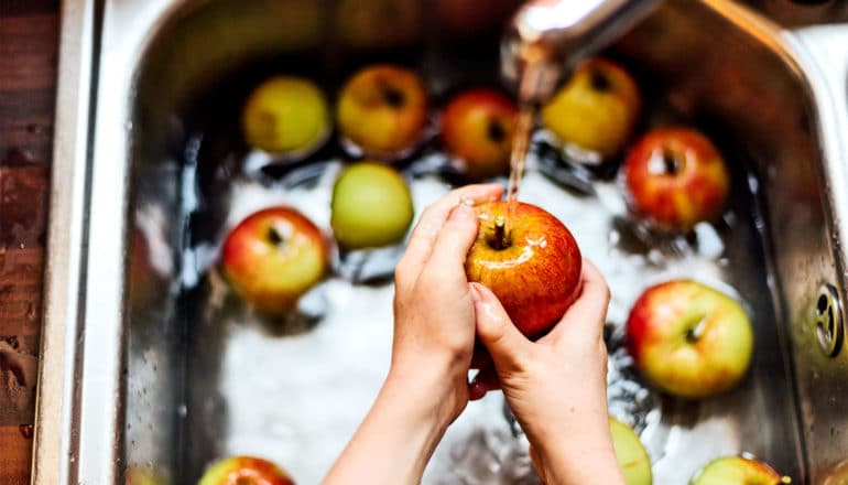 A person washes apples in their sink