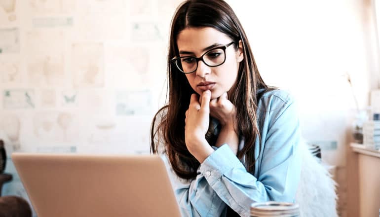 A woman looks stressed as she stares at her laptop screen