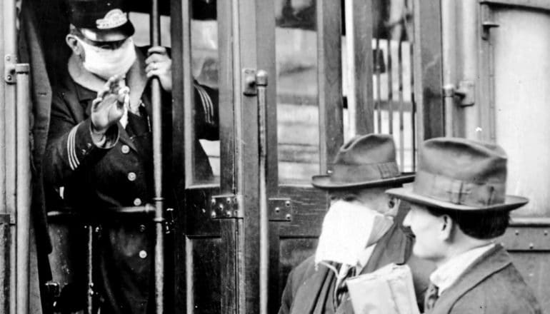 A tram worker waves away a man who's not wearing a face mask