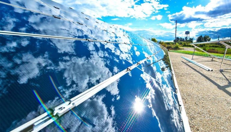 A solar panel reflects the clouds in the sky