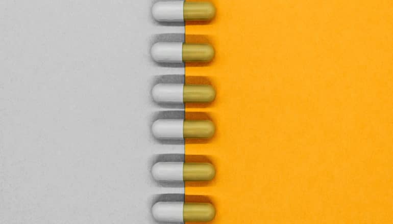 vertical row of capsules aligns gray caps with gray paper and orange caps with orange paper beneath