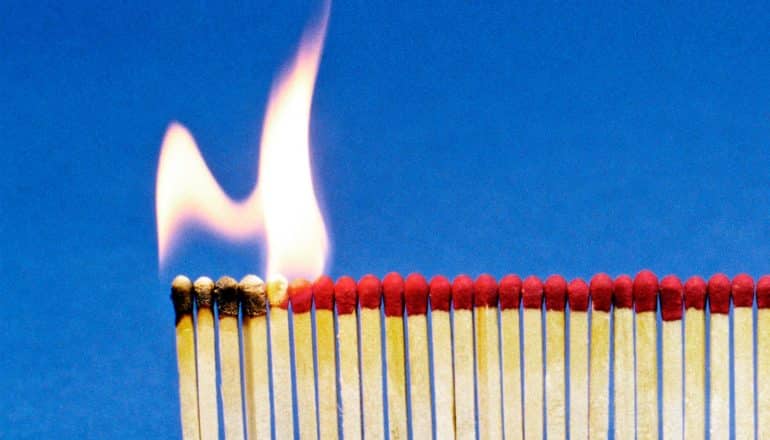 Fire burns through a line of matches against a blue background