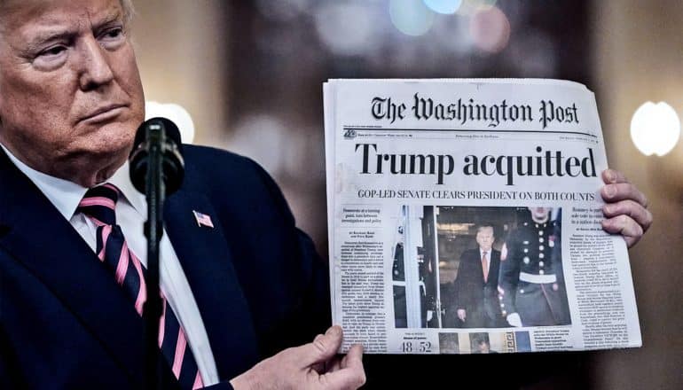 Donald Trump holds up a newspaper with the headline "Trump acquitted"