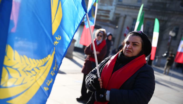 serious adult holds blue flag outdoors