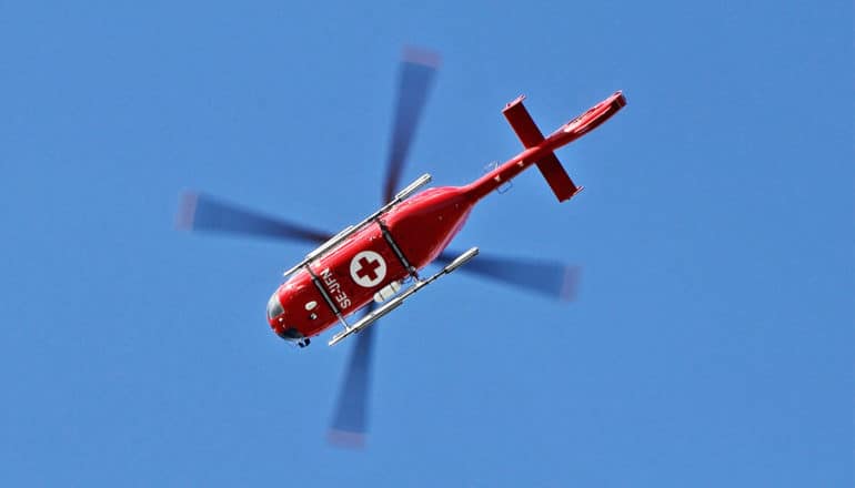 An air ambulance flies through a deep blue sky