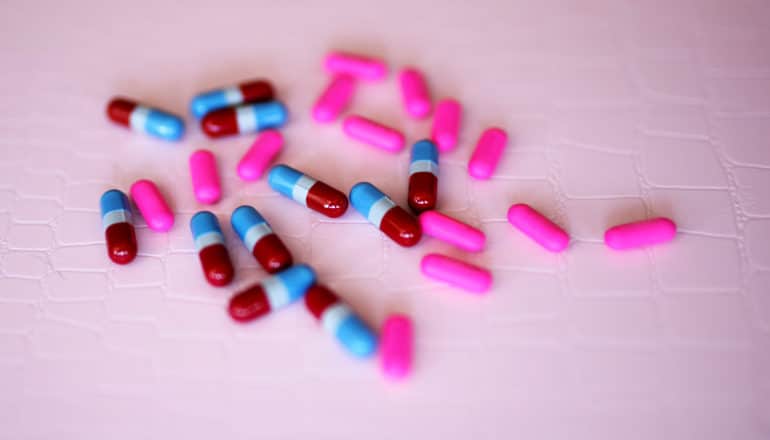 bright colored pills on pink background