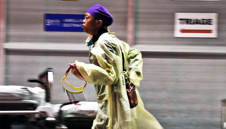 A medical worker in a gown runs towards an emergency