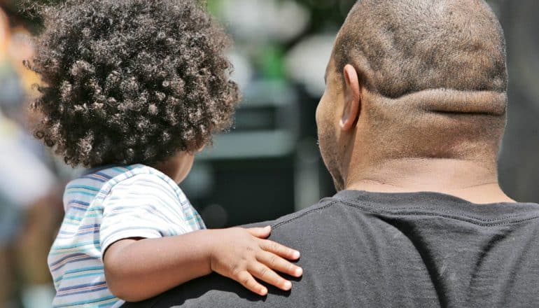 rear view of adult man carrying toddler