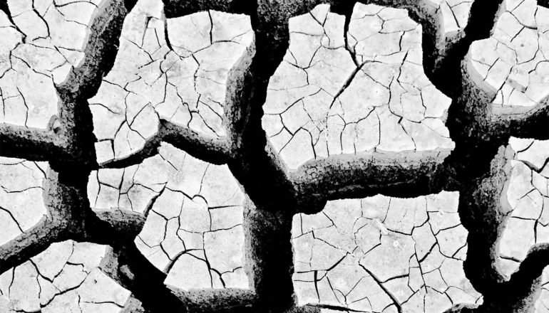 A black and white shot of dried out earth, cracking in the heat