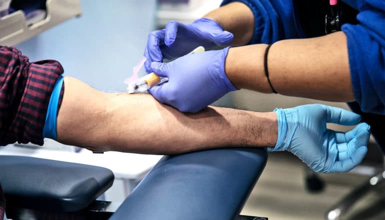 A nurse draws blood for a COVID-19 antibody test