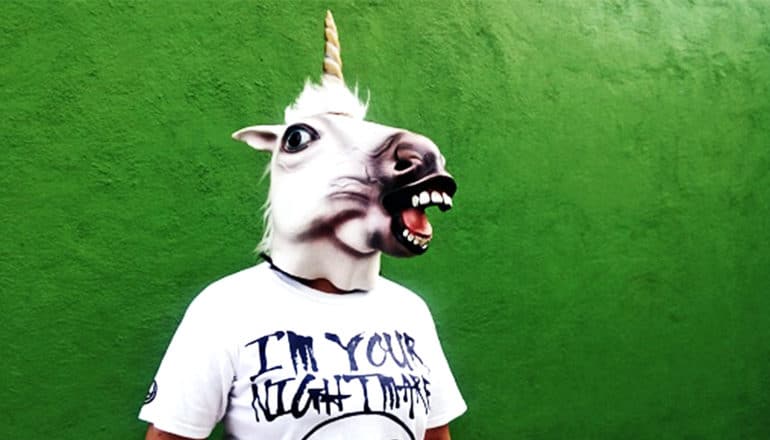 A person has a unicorn mask on as well as a t-shirt that reads "I'm your nightmare"