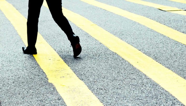 A person walks on a street with yellow lines