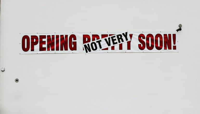 sign says "opening not very soon" with "not very" covering up "pretty"