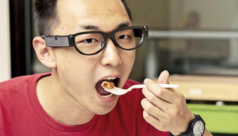 A researcher takes a bite of food while wearing Fitbyte on his glasses