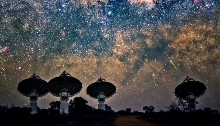 Large satellite dishes point at the starry night sky