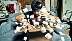 A young man digs through packing peanuts in large box