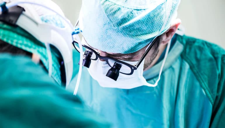 A surgeon looks down at a patient