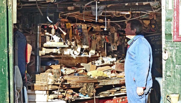 A man stands in a cluttered garage