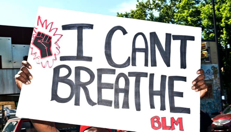 A man holds a sign that reads "I Can't Breathe"