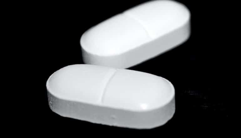 Two white pills sit on a black background