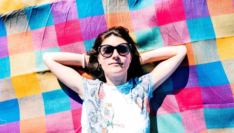 A young woman lays on a colorful blanket