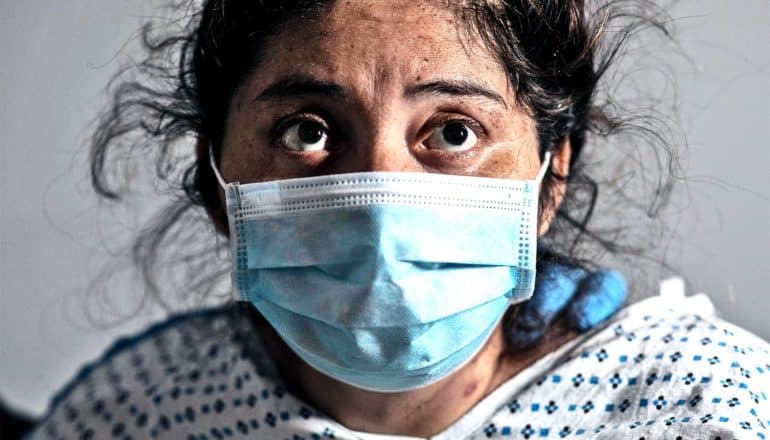 A woman looks worried while wearing a blue medical mask