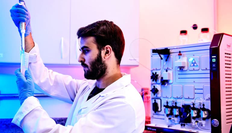 A researcher pipes liquid into a vial in a lab