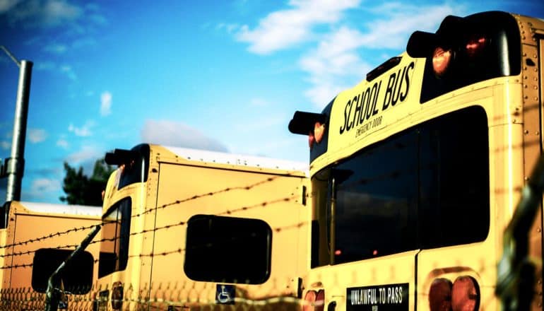 school buses behind wire fence