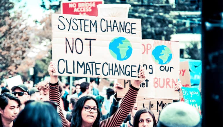 A climate protester holds a sign that reads "System change not climate change."