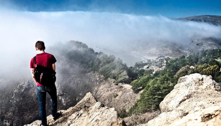 A man looks down at fog over Muir Woods in California