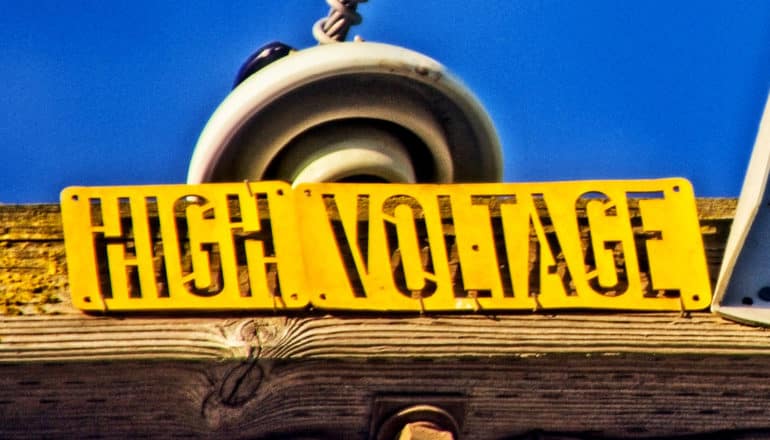 A sign on a power line reads "High Voltage"