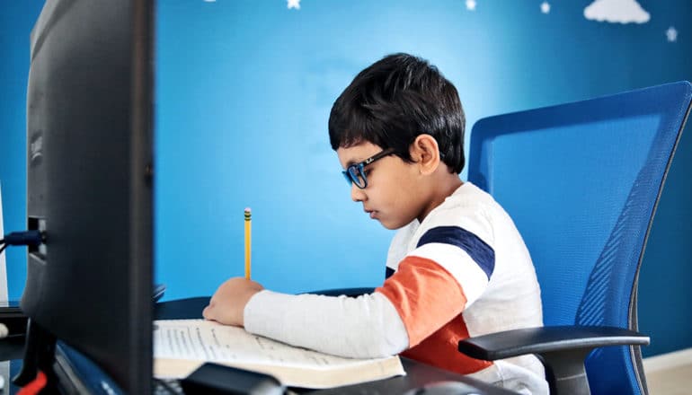 A young boy does his school work from home in front of a computer